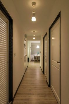 a long hallway with white walls and wooden floors is lit by recessed light fixtures