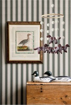 two ducks sitting on top of a dresser next to a wall with a painting hanging above it