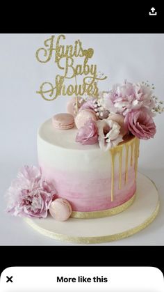 a pink and gold baby shower cake with flowers on top