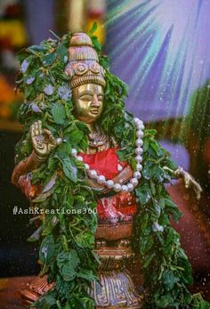 the statue is covered in greenery and beads