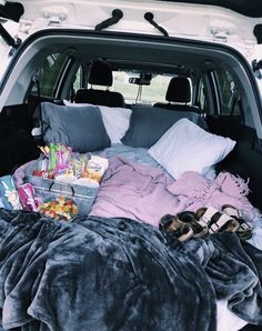 the back end of a white truck filled with blankets and other items, including shoes