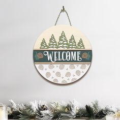 a wooden sign hanging from the side of a christmas tree with pine cones and snow