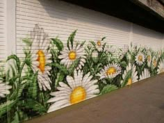 the mural on the side of a building is painted with daisies