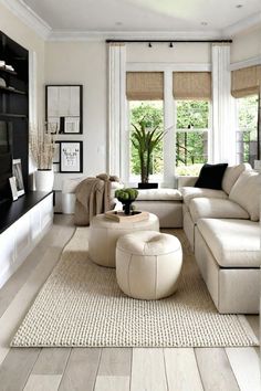 a living room filled with white furniture and lots of natural wood flooring next to a large window