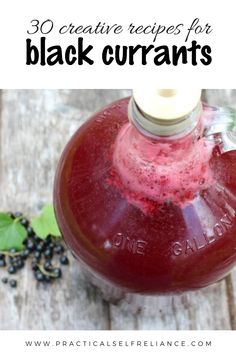 a bottle filled with black currans sitting on top of a wooden table next to berries