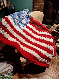 an american flag crocheted blanket sitting on top of a chair in front of a fireplace