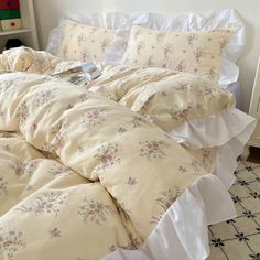 an unmade bed with white sheets and floral print on the comforter is shown