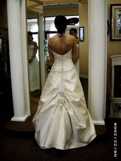 a woman in a wedding dress looking at herself in the mirror