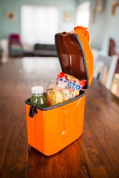 an orange lunch box sitting on top of a wooden table