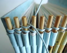 several blue and yellow umbrellas with wooden poles attached to the top, in front of a white wall