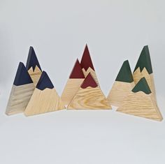 three wooden mountains with different colors and sizes on them, sitting side by side in front of a white background