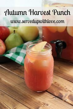 a jar filled with liquid sitting on top of a wooden table next to some apples