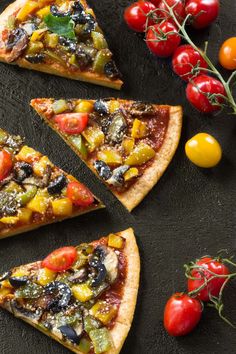 four slices of pizza with different toppings on top of them next to tomatoes and cherry tomatoes