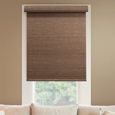 a living room with a white couch and brown roller shades on the window sill