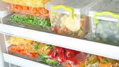 plastic containers filled with vegetables and fruits on the shelves in a refrigerator or freezer