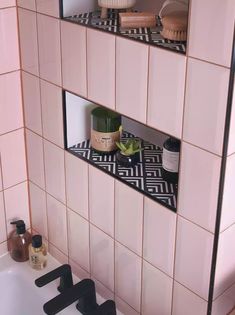 the bathroom is decorated in pink and black with white tiles on the walls, along with shelves that hold personal care items