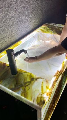 a woman is washing her hands in a marble sink with a black faucet