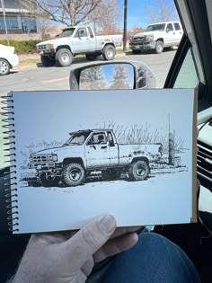 a person holding up a drawing of a truck in the back seat of a car