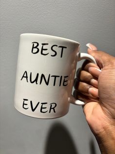 a person holding a white coffee mug with the words best annte ever written on it