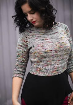 a woman with black hair wearing a multicolored sweater