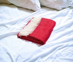 a red and white blanket laying on top of a bed