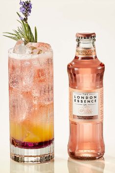 a bottle of london dry gin next to a tall glass filled with ice and garnish