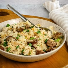 a bowl filled with rice and vegetables on top of a wooden table