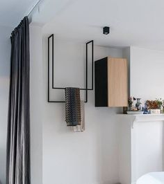 a white bed sitting in a bedroom next to a wall mounted shelf with towels on it