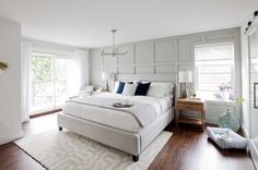 a large white bed sitting in a bedroom on top of a hard wood floor