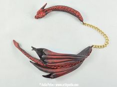 a red and black bird shaped necklace on a gold chain