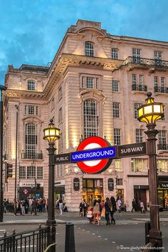 people are walking on the street in front of a building with a sign that says underground subway