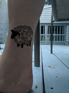 a black sheep tattoo on the foot of a person's leg with spirals around it