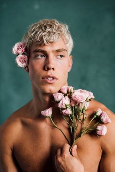 a shirtless man holding pink roses in his hand