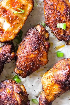 grilled chicken wings with green onions and seasoning on parchment paper, ready to be eaten