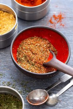 three bowls filled with different types of seasoning next to measuring spoons on a table