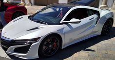 a white sports car is parked in front of a man standing next to another one