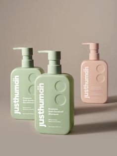 three bottles of shampoo sitting next to each other on a gray surface with one bottle in the foreground