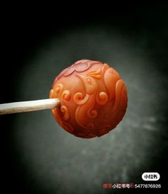 an orange carved object is being held by a wooden stick with chopsticks in it