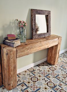 a wooden bench sitting next to a mirror and vase with flowers on top of it