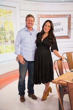 a man and woman standing next to each other in front of a table with chairs