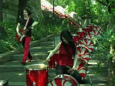 two women are playing drums in front of some red and white drum sets on the steps