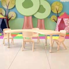 children's table and chairs in front of a colorful wall with trees on it