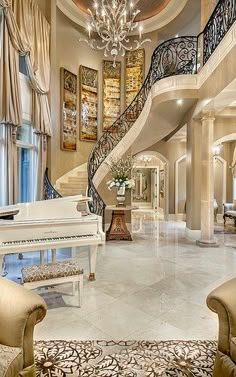 a grand piano in the middle of a living room with chandelier and stairs