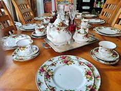 a dining room table with china on it and plates, cups, and saucers