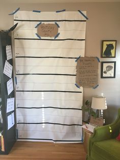 a room with a black and white striped wall hanging on it's side next to a green chair