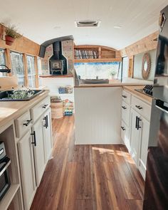 a kitchen with wood flooring and white cabinets next to a stove top oven in a trailer