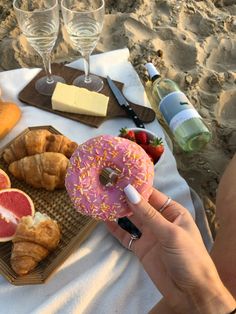 a person holding a doughnut in front of food on a table at the beach