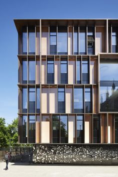 a building with lots of windows on the side of it and people walking in front of it