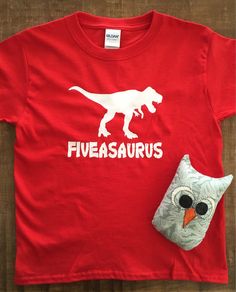 a red t - shirt with an image of a dinosaur on it