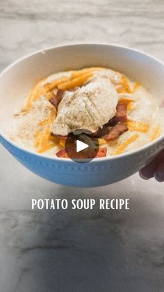 a person holding a bowl of food on top of a marble countertop with the caption potato soup recipe